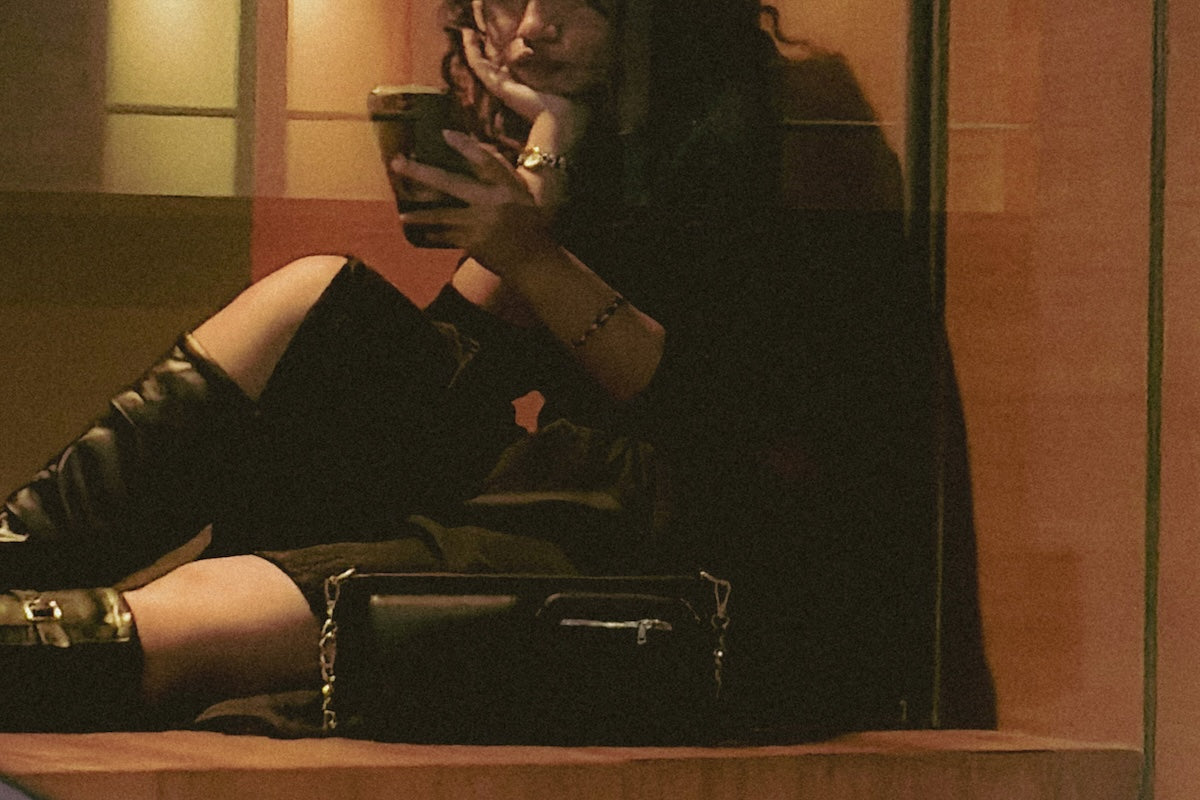 girl using her phone sitting with black bag