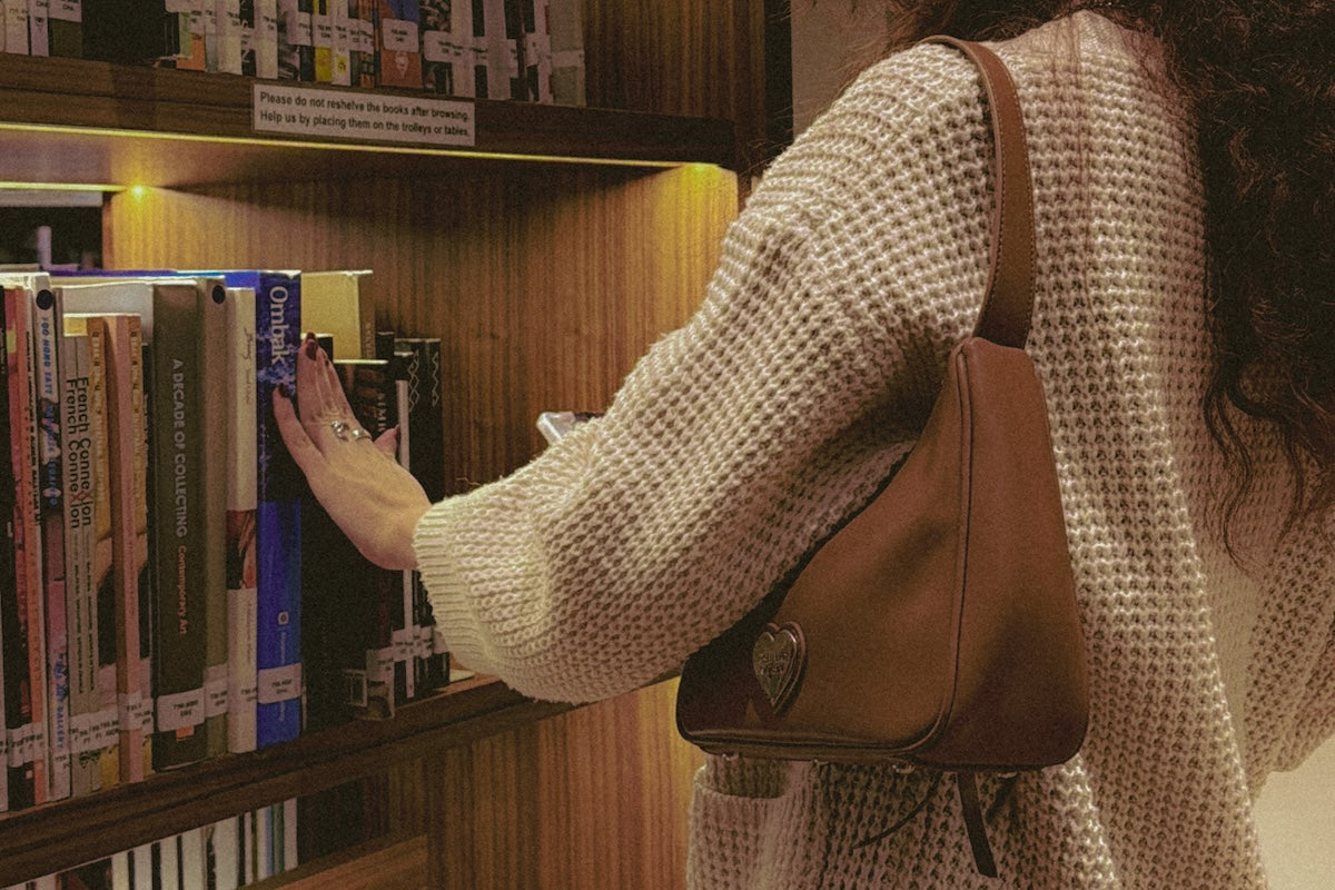 girl picking out books carrying brown bag