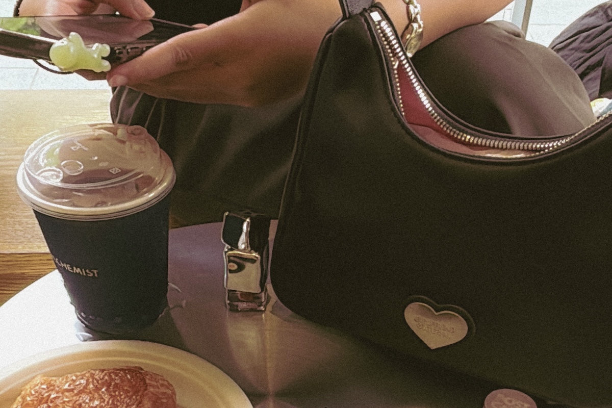 black bag on table with coffee and pastry